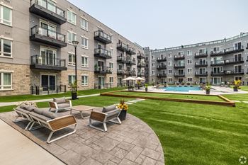 A large apartment complex with a pool and a patio with chairs.